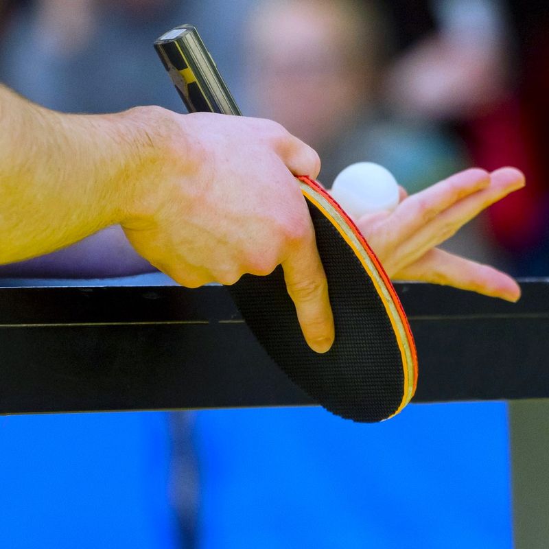 a close up image of a ping pong players hand about to serve a ping pong ball