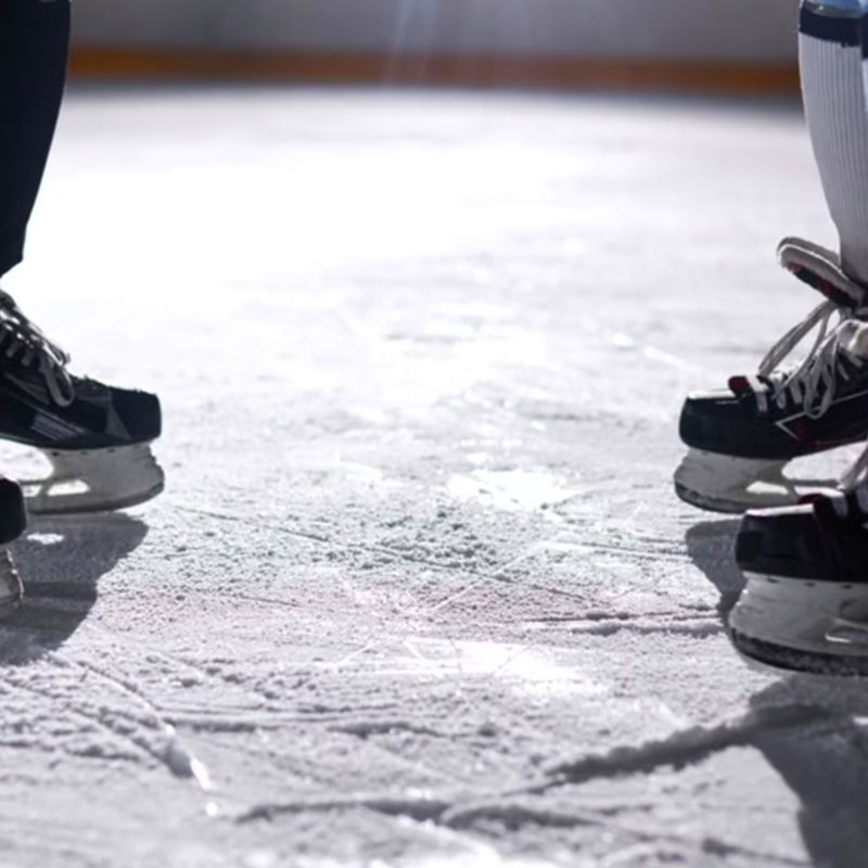 two ice hockey players feet wearing hockey skates on ice