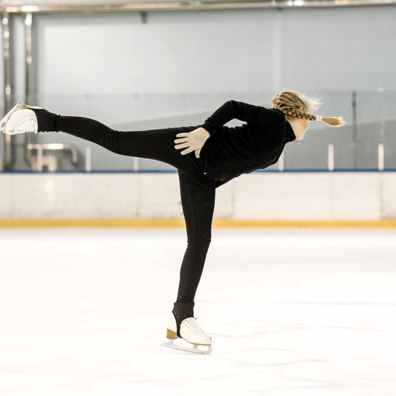 a youth female figure skating on an ice rink