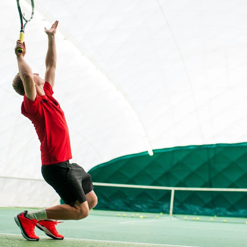 a male tennis player bending his knee before jumping to serve a tennis serve