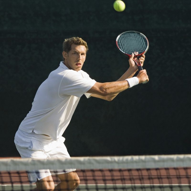 a male adult tennis player about to return the tennis ball