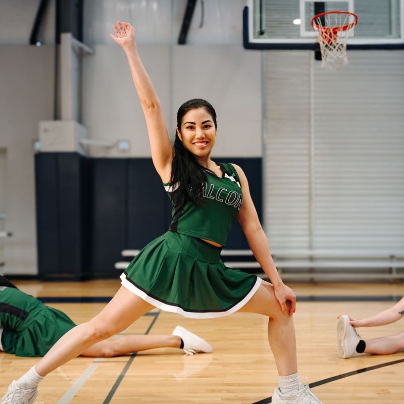 Girl posing between two cheerleaders in splits